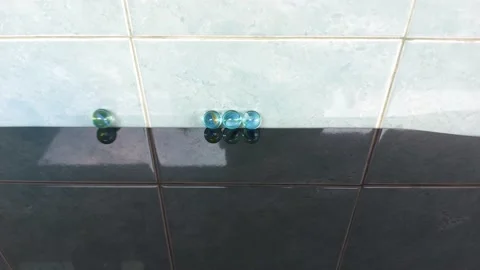 Glass marble balls, rolling hitting clashing on black glass table Video stock 209145492