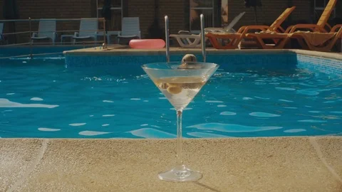 A glass of martini near the pool. girl dives into the pool Stock Footage