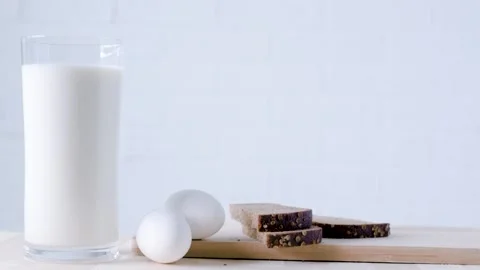 Glass of milk, bread and eggs on the wooden table, copy space, closeup Stock Footage 197008270