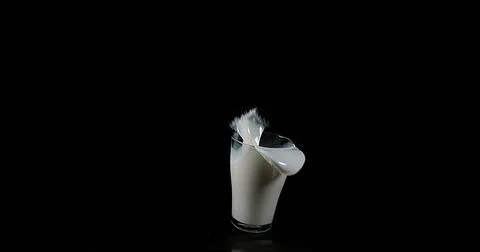Glass for Milk exploding against Black Background Stock Photos