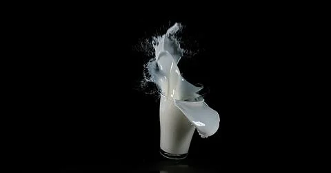 Glass for Milk exploding against Black Background Foto stock
