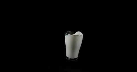 Glass for Milk exploding against Black Background Foto stock