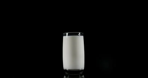 Glass of Milk Exploding against White Background Stock Photos