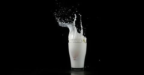 Glass of Milk Exploding against White Background Stock Photos