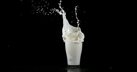 Glass of Milk Exploding against White Background Stock Photos