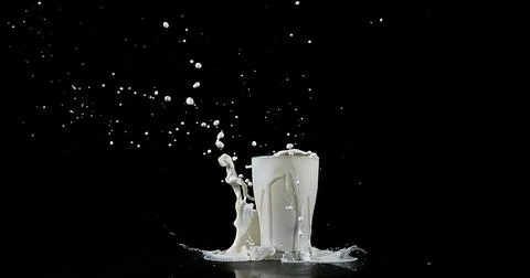 Glass of Milk Exploding against White Background Foto stock