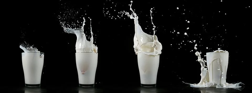 Glass of Milk Exploding against White Background Foto stock