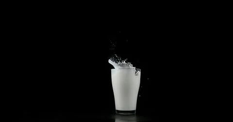 Glass of Milk Exploding against White Background Stock Photos