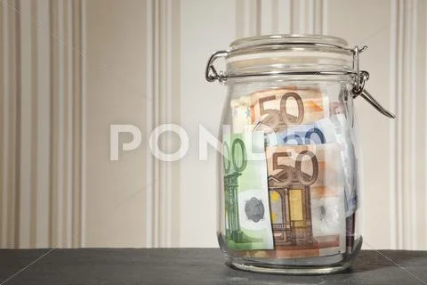 Glass Money Jar With Euro Notes Inside On A Table