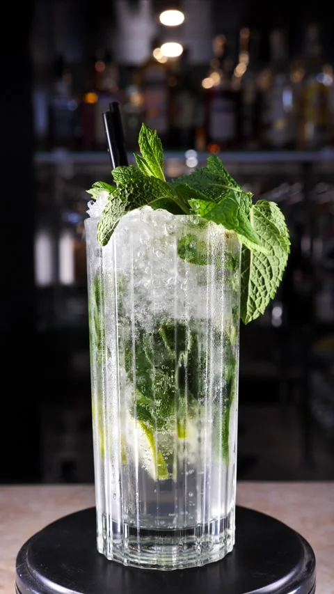 Glass with moxito cocktail rotating on bar counter. Vertical screen Stock Footage 313367015