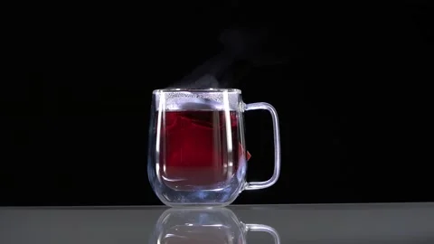 A glass mug with red fruit tea evaporates on a black Stock Footage 144431212