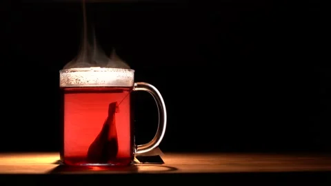 A glass mug with red fruit tea evaporates on a black background Stock Footage 144431275