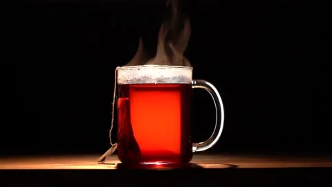 A glass mug with red fruit tea evaporates on a black background Stock Footage 144431388