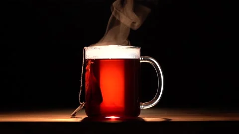 A glass mug with red fruit tea evaporates on a black background Stock Footage 144431391