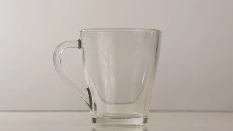 In a glass mug on the table put a ball of green tea and pour boiling water. Stock Footage 120940350