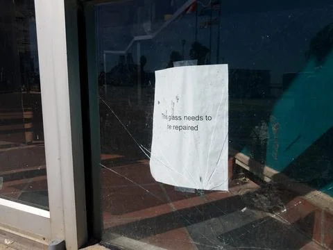 This glass needs to be repaired sign on broken window Stock Photos