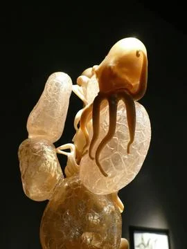 Glass octopus sculpture clinging to translucent rocks on a black background.. Stock Photos