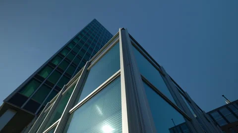 Glass office building with panoramic windows reflecting sun disk low angle shot Stock Footage 309139470