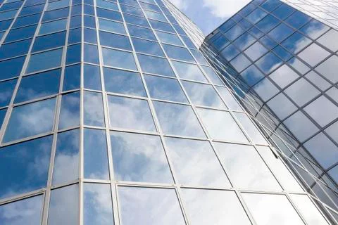 Glass office facade reflects clouds and blue sky Stock Photos