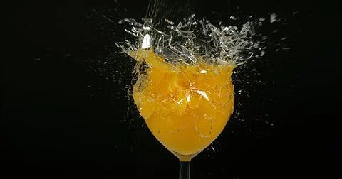 Glass of Orange Exploding against Black Background 스톡 사진