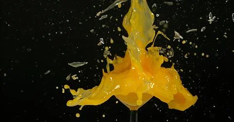 Glass of Orange Exploding against Black Background Stock Photos