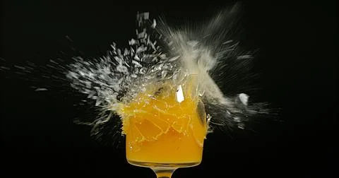 Glass of Orange Exploding against Black Background Stock Photos