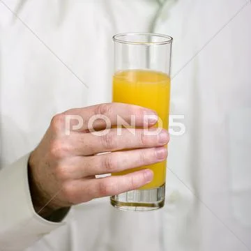 Glass with orange juice in a hand Stock Photos