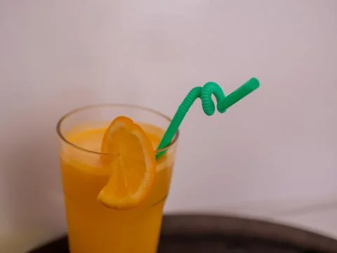 A glass of orange juice with an orange slice and a straw. Stock Photos