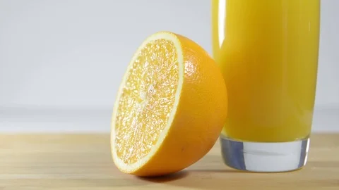 ​​glass of orange juice is on the table. Half an orange in the background. Stock Footage 124084075