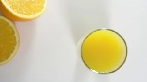 Glass of orange juice is on the table. Half an orange in the background. Stock Footage 124084081