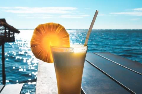 Glass of pineapple juice with blue sky lake in background Stock Photos