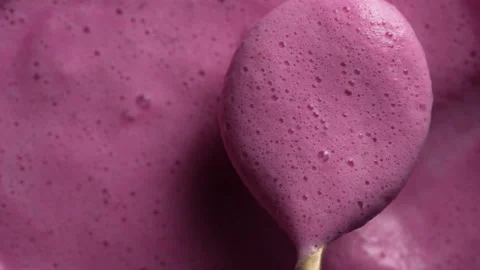 Glass of pink raspberry milkshake and spoon. Milk smoothie surface with bubbles Stock Footage 295966481
