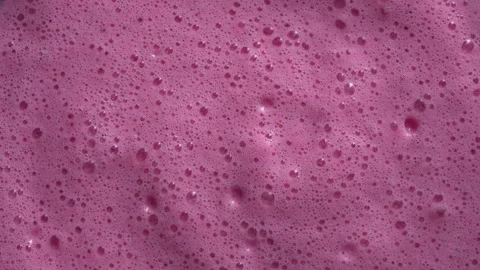 Glass of pink raspberry milkshake. Milk smoothie surface with bubbles, rotate Stock Footage 296182511
