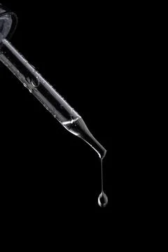 Glass pipette with drop on black background Stock Photos