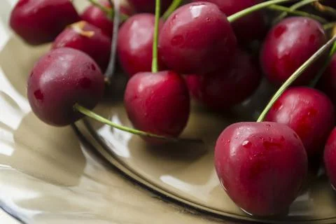 ON a glass plate are red cherry berries. Cherries on a plate. Close-up of the Stock Photos
