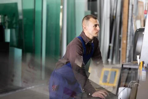 Glass processing factory worker operating CNC machine Stock Photos