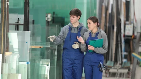 In glass processing workshop, girl supervisor with documents and young man Stock Footage 313459991