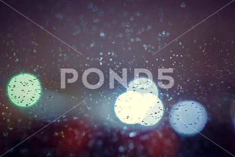 Glass with raindrops and lights out of focus Stock Photos