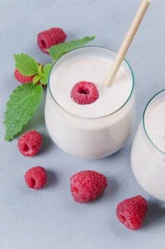 Glass of raspberry milkshake on gray background Stock Photos