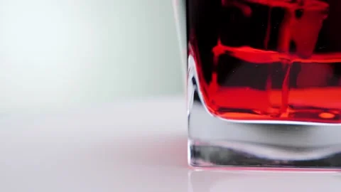 Glass of red beverage with ice cubes slowly rotates over white background. Stock Footage 130823235