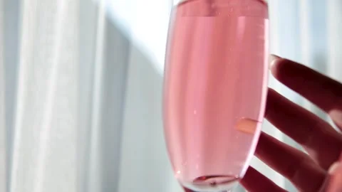 A glass of red champagne, inside which is a wedding ring in the hands of a lady Stock Footage 249010046