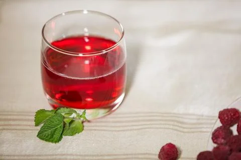 Glass of red raspberry juice with mint on a linen tablecloth with copy space. Stock Photos