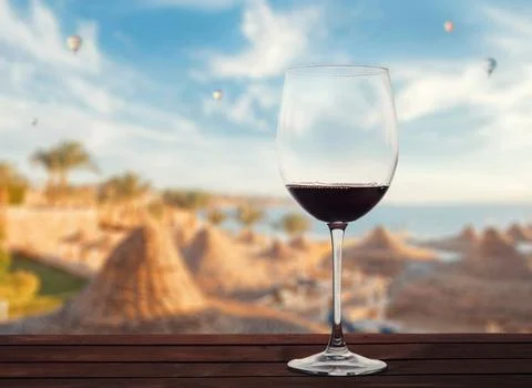 Glass of red wine against the backdrop of the sea beach and balloons Stock Photos