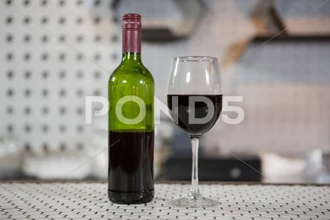 Glass of red wine and bottle on counter Stock Photos