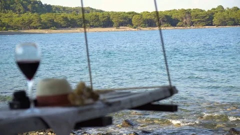 Glass of red wine and hat on a Wooden table at the sunset Stock Footage 93088779
