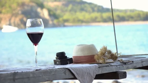Glass of red wine and hat on a Wooden table at the sunset Stock Footage 93089048