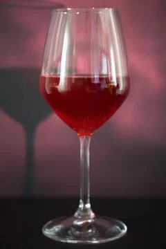 A glass of red wine, the background is reddish, the tank is illuminated with Stock Photos