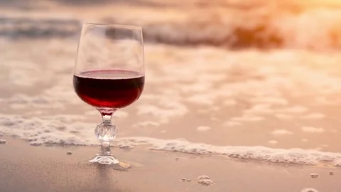 Glass of red wine on the beach at sunset. Sea waves Stock Footage 80323696