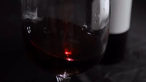 Glass of red wine on a dark background. Slow motion Vídeo Stock 163373441