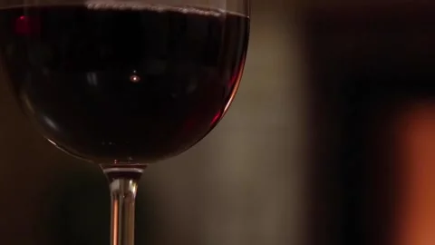 Glass of Red Wine, a fireplace in the background is burning Stock Footage 147094671